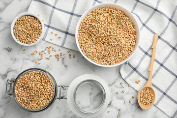Uncooked green buckwheat grains on white marble table, flat lay