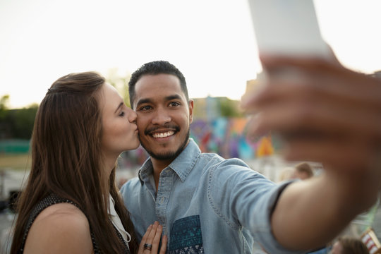 Affectionate Young Couple Kissing And Taking Selfie With Camera Phone