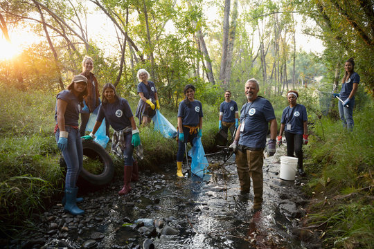 Portrait confident people volunteering, cleaning up garbage in stream