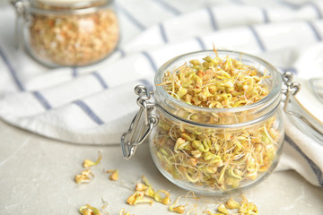 Jar of sprouted green buckwheat on light table, closeup