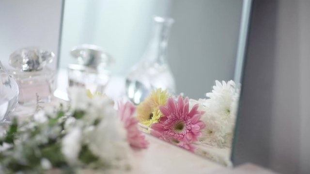 Move Camera From Right to Left, Reflection in Mirror A Bouquet of Bloom White, Pink and Yellow Daisy Flower and Glass Vase and Perfume on Dressing Table  