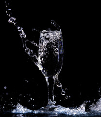 Water with splashes in a glass on a black background