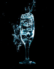 blue water with splashes in a glass on a black background