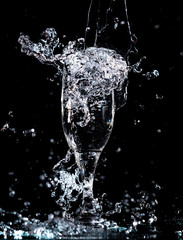 Water with splashes in a glass on a black background