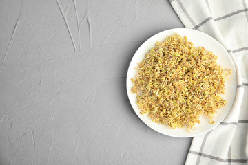 Plate with sprouted green buckwheat on light grey table, top view. Space for text
