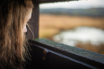 A Young Woman Looks Out From a Bird Hide By A Scottish Loch