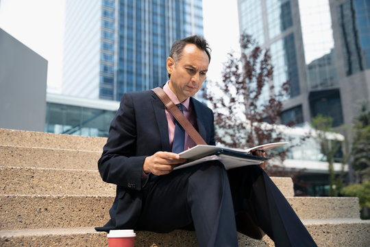 Businessman reading paperwork in urban plaza