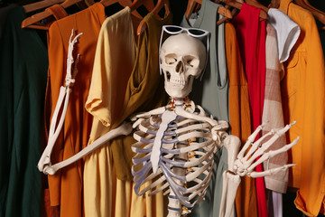 Artificial human skeleton model among clothes in wardrobe