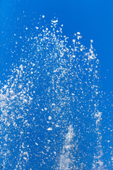 Splashing water from a fountain on a background of blue sky
