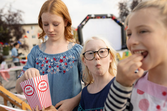 Portrait Sisters Enjoying Popcorn At Movie In The Park