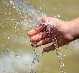Fototapeta premium Hand of a girl in the spray of water of the fountain