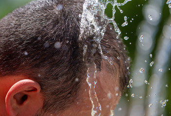 The head of a man in the spray of water of the fountain