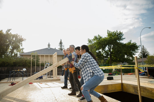 Volunteers lifting frame, helping build house