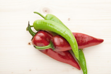 Red and green peppers on a wooden background.