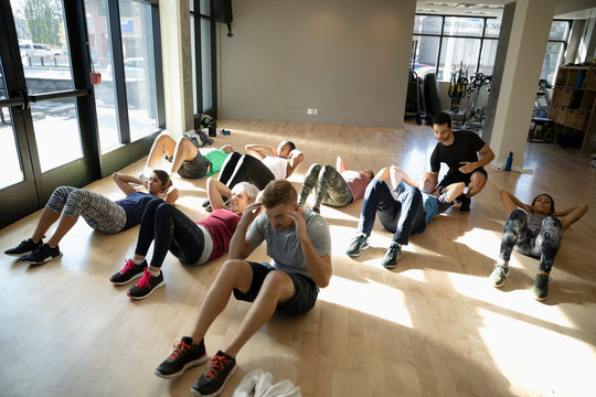 Group Exercise Class Doing Sit-ups In Gym Studio