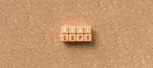 cubes with text REAL and COPY on cork background