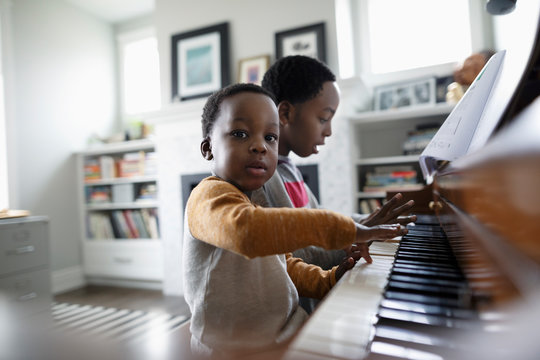 Portrait cute toddler boy playing piano with brother