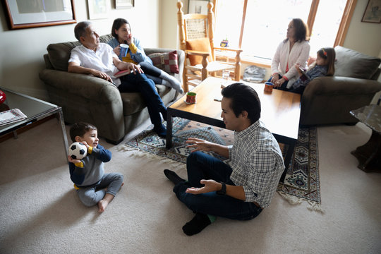 Latinx multi-generation family talking and playing with soccer ball in living room