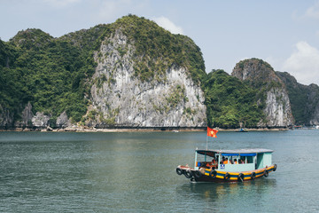 Fototapeta na wymiar Tourist cruise ship sailing among limestone mountains in Halong Bay, Vietnam