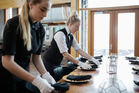 Female Waitresses Setting Restaurant Table With White Gloves