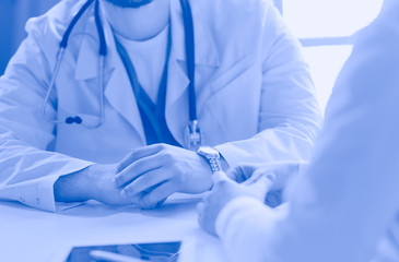 Portrait of a male doctor with laptop sitting at desk in medical office