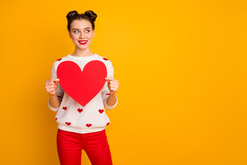 Photo of pretty lady hold paper heart demonstrate creative idea postcard date invitation wear white red hearts pattern print sweater pants isolated yellow color background