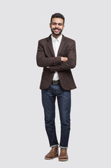 Handsome smiling young man full length studio portrait, isolated on gray background