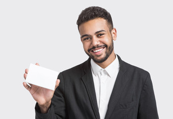 Happy smiling young business man showing blank card, isolated over gray background. Handsome man with white card	