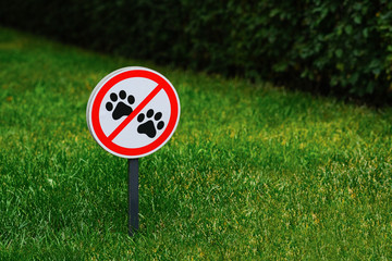 Sign on lawn prohibiting walking pets. Prohibition of dog walking in park area.