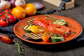 Top view delicious grilled vegetables with vegetables and spices on black stone background. Barbecued healthy food.