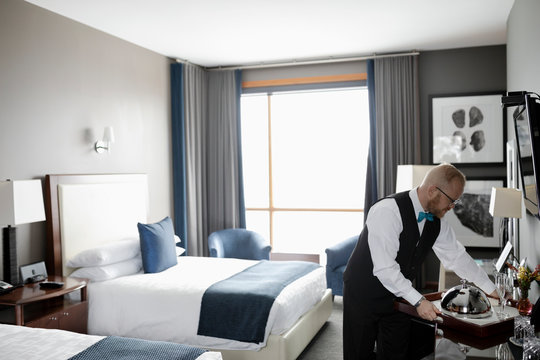 Male hotel staff waiter serving food in luxury hotel room