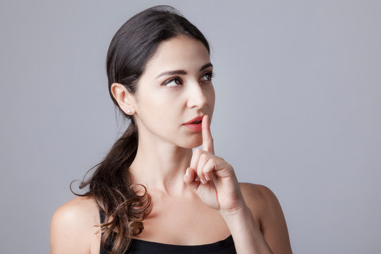 bella e giovane donna fa il segno del silenzio con le mani - isolata su sfondo grigio