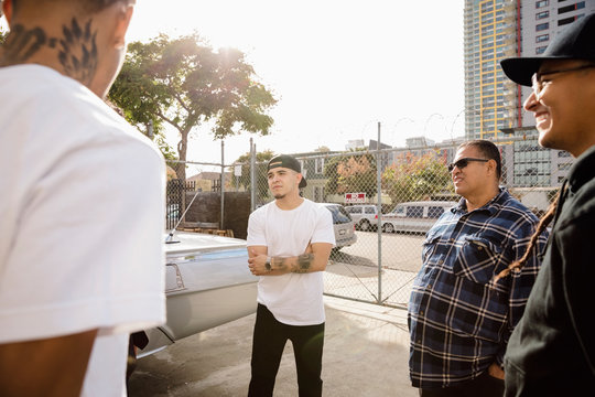 Latinx Men Friends Talking, Hanging Out In Urban Parking Lot