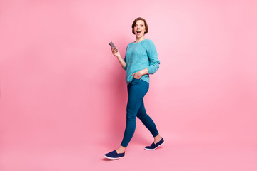 Full length body size view of her she nice attractive lovely pretty cheerful cheery glad brown-haired girl using cell 5g app chatting walking isolated over pink pastel color background
