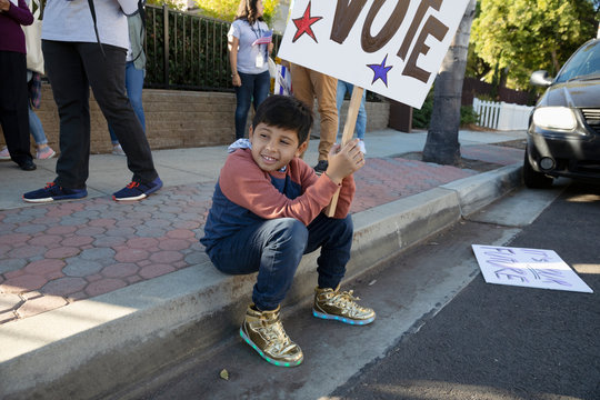 Latinx boy volunteering, canvassing voters on curb