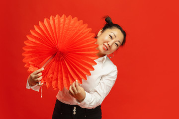 Happy Chinese New Year 2020. Asian young woman holding big lantern on red background in traditional clothing. Smiling, cute, looks happy. Celebration, human emotions, holidays. Copyspace for ad.