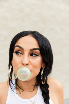 Latinx young woman blowing bubble with gum