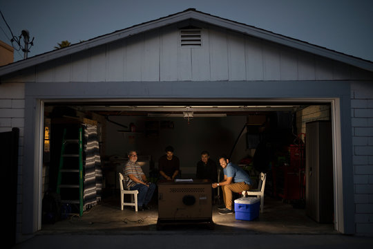 Latinx Men Watching Sports On TV In Garage At Night