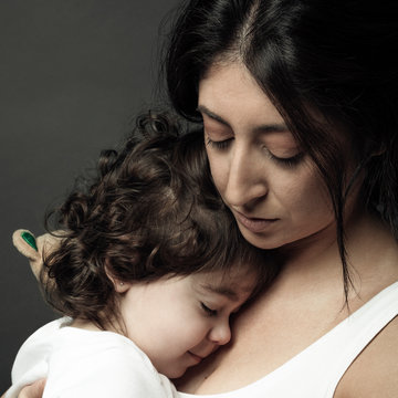 Serene Latina woman holding toddler daughter