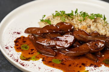 Baked lamb tongues with spicy bulgur porridge in a white plate