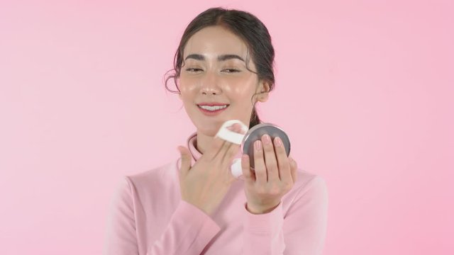 Woman face with nice applies make up by Compact Powder brush on pink background