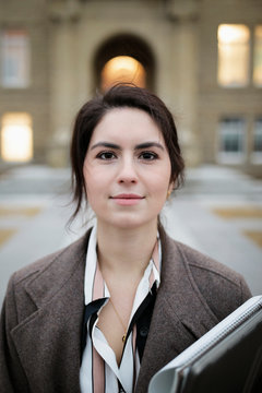 Portrait confident female university student standing outside school building