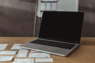 Selective focus of laptop with blank screen and website wireframe sketches on table