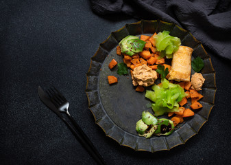 Trendy vegetarian dish. Bowl with sweet potato, zucchini noodles, hummus, omelette, avocado, flax seeds and celery. Vegetarian Bowl. Healthy eating concept. Top view, dark background