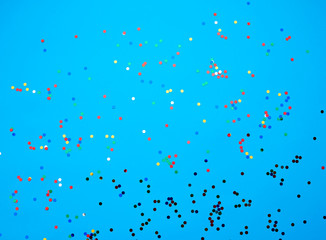 Fototapeta na wymiar shiny multicolored round confetti scattered on a blue background