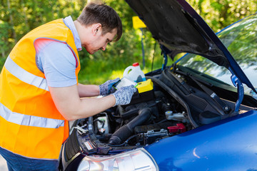 Mechanic in an orange vest with a diagnostic tablet checks the car engine. scheduled maintenance and diagnostics of the car engine. Mechanic With Digital Tablet Showing Graph While Examining Car