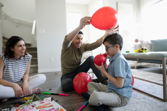 Playful father with balloon creating static with son‚Äö√Ñ√¥s hair