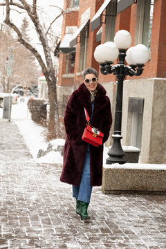 Portrait happy, stylish woman walking along snowy sidewalk