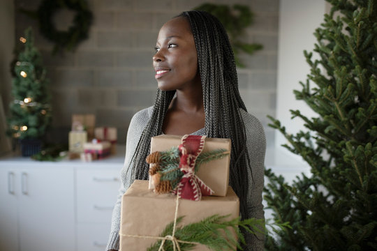 Smiling young woman carrying Christmas gifts