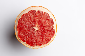 Slice of red dry grapefruit on gray background with shadow